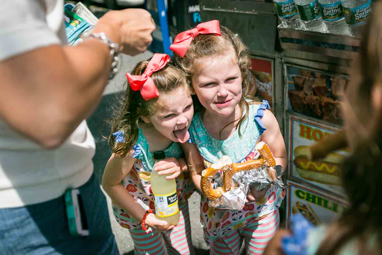 Two little girls making funny faces and holding a pretzel