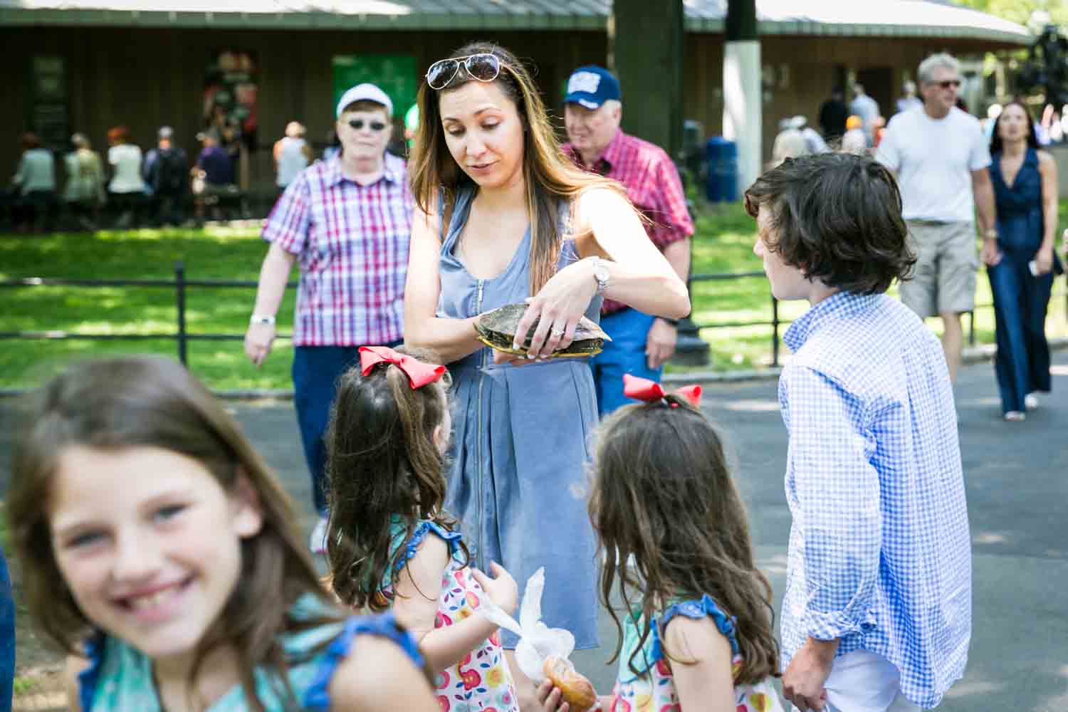 Woman holding a turtle in front of children for an article on how to get natural smiles out of children