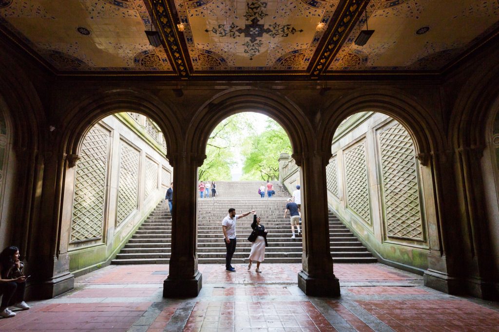 Couple dancing under mosaic arch in Central Park for an article on NYC rainy day photo tips