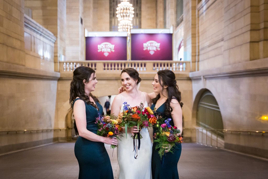 Two bridesmaids and bride laughing in Grand Central Terminal