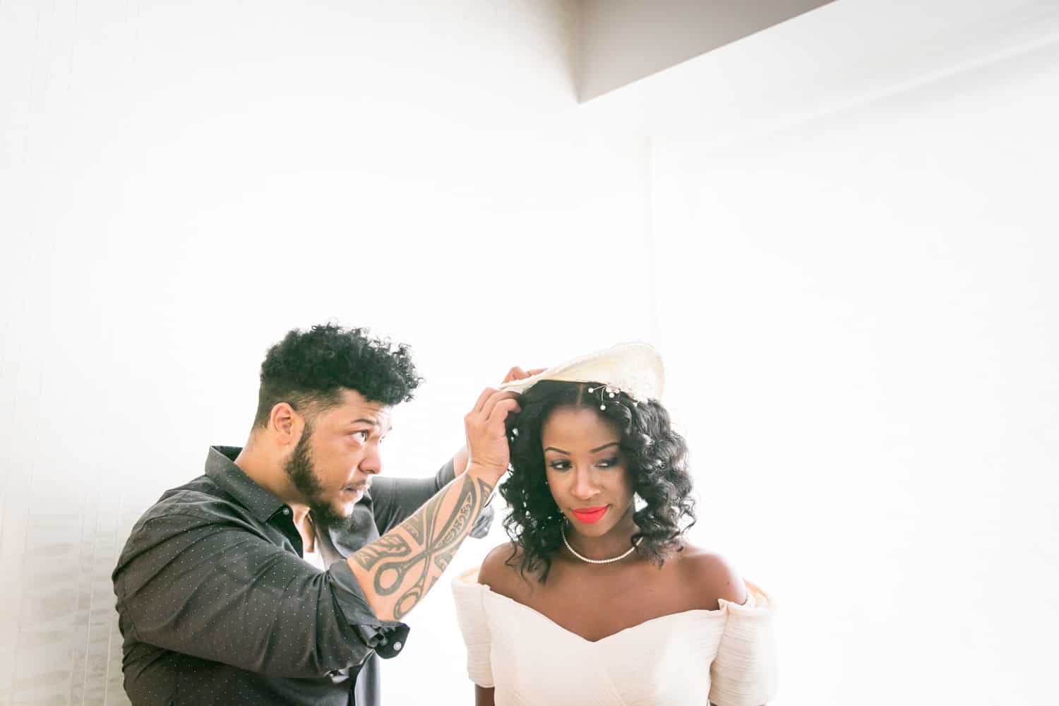 Hair stylist helping bride with hat