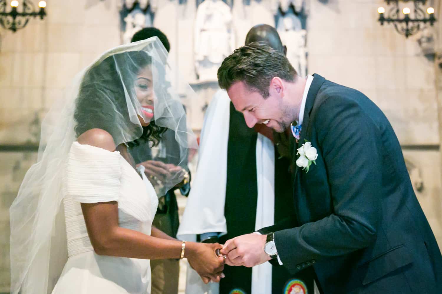 Groom putting ring on bride's finger in a Trinity Church wedding
