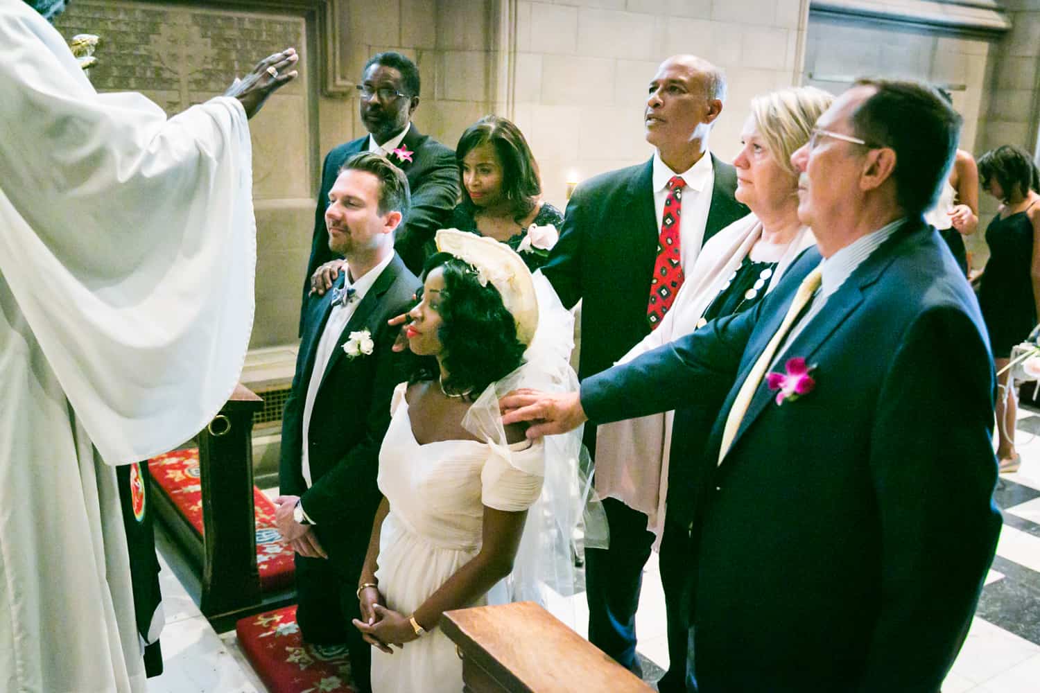Guests with hands on bride and groom during Trinity Church wedding ceremony