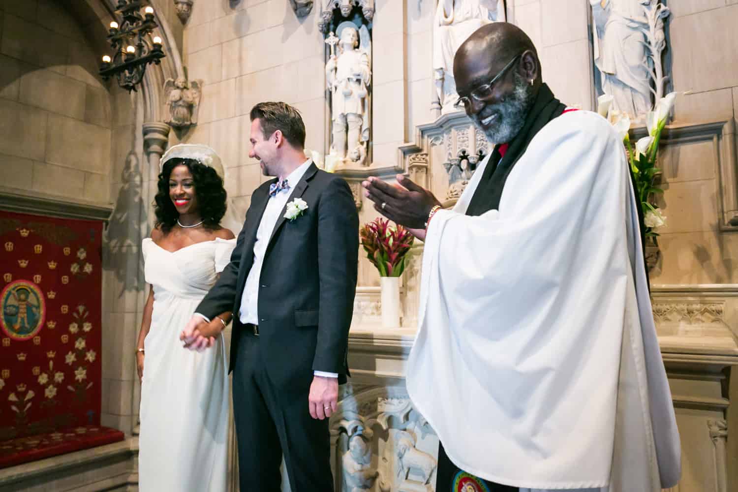Priest clapping for bride and groom during Trinity Church wedding ceremony