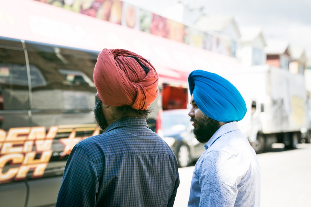 Two men wearing colored turbans on the streets of Richmond Hill, Queens