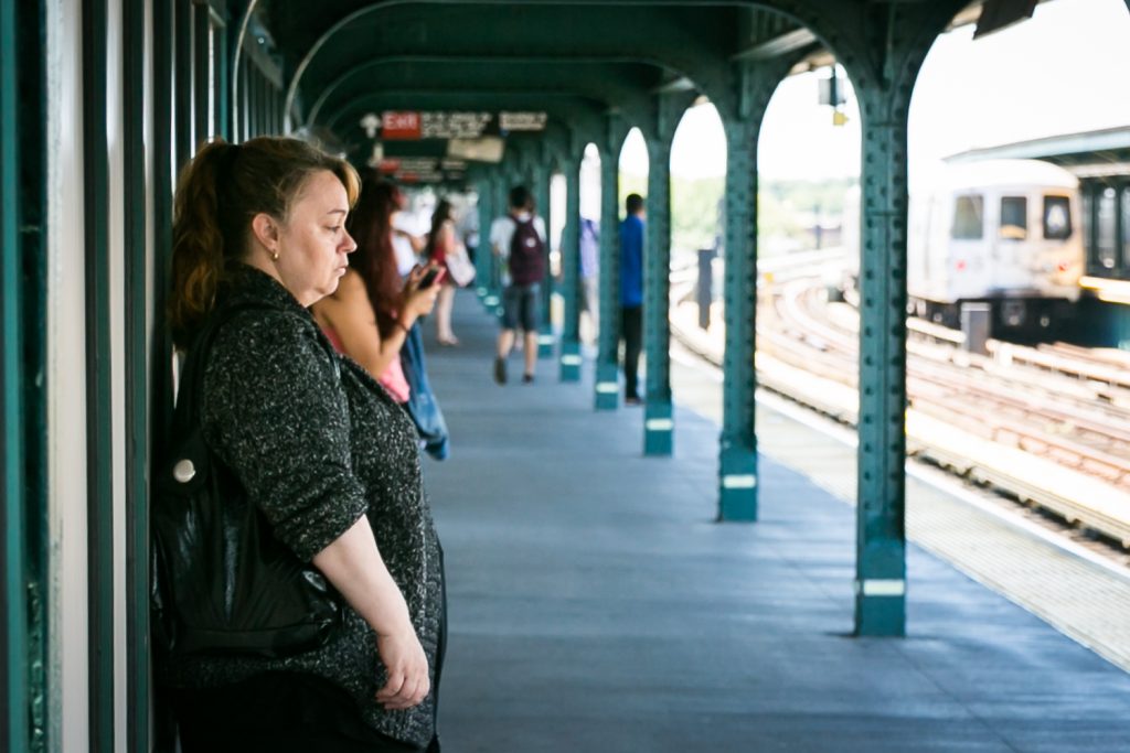 Woman staring ahead waiting for train in subway platform