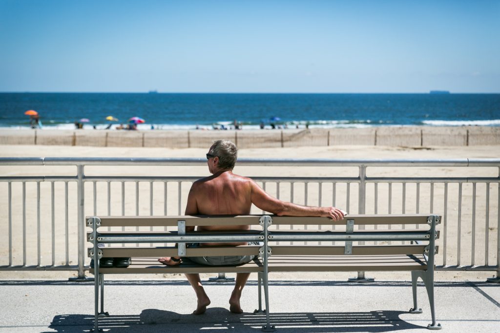 Older man sitting on bench on Far Rockaway beach boardwalk