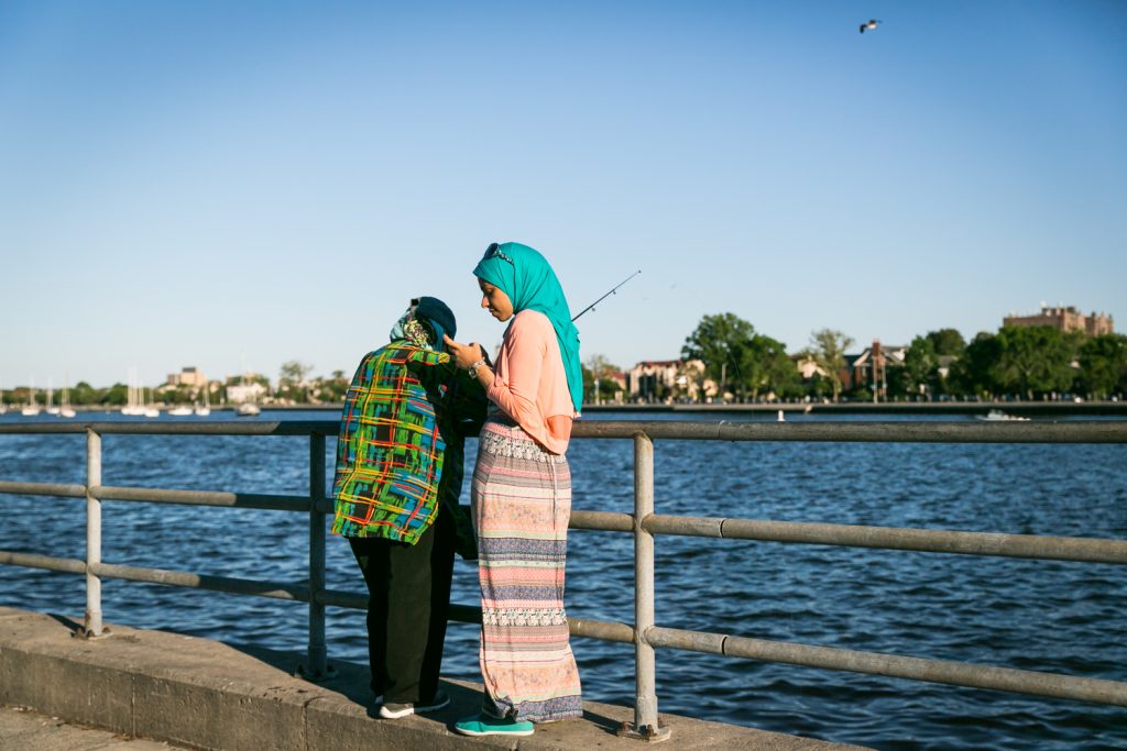 Muslim woman wearing blue hijab standing by waterfront railing in Sheepshead Bay, Brooklyn