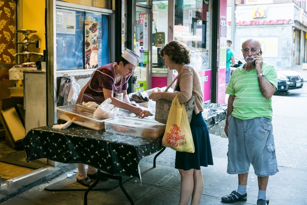 Woman buying from street vendor with man on cell phone in Sheepshead Bay, Brooklyn