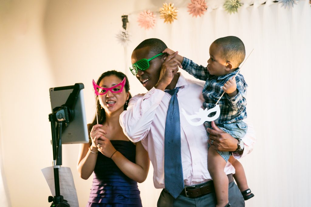 Little boy grabbing his father's glasses in photo booth for an article on event entertainment ideas