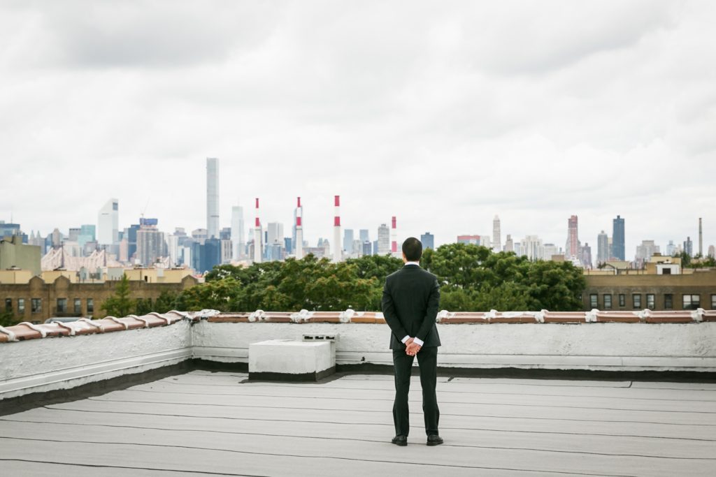 Groom turned around watching NYC skyline waiting for first look