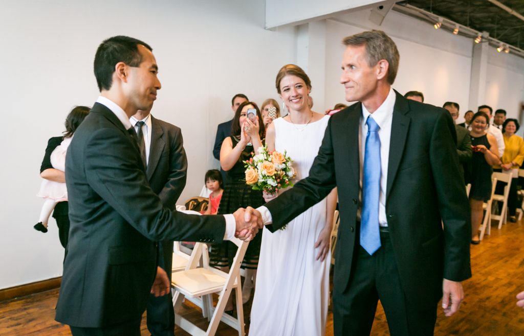 Groom shaking hand of father of the bride during Astoria wedding ceremony