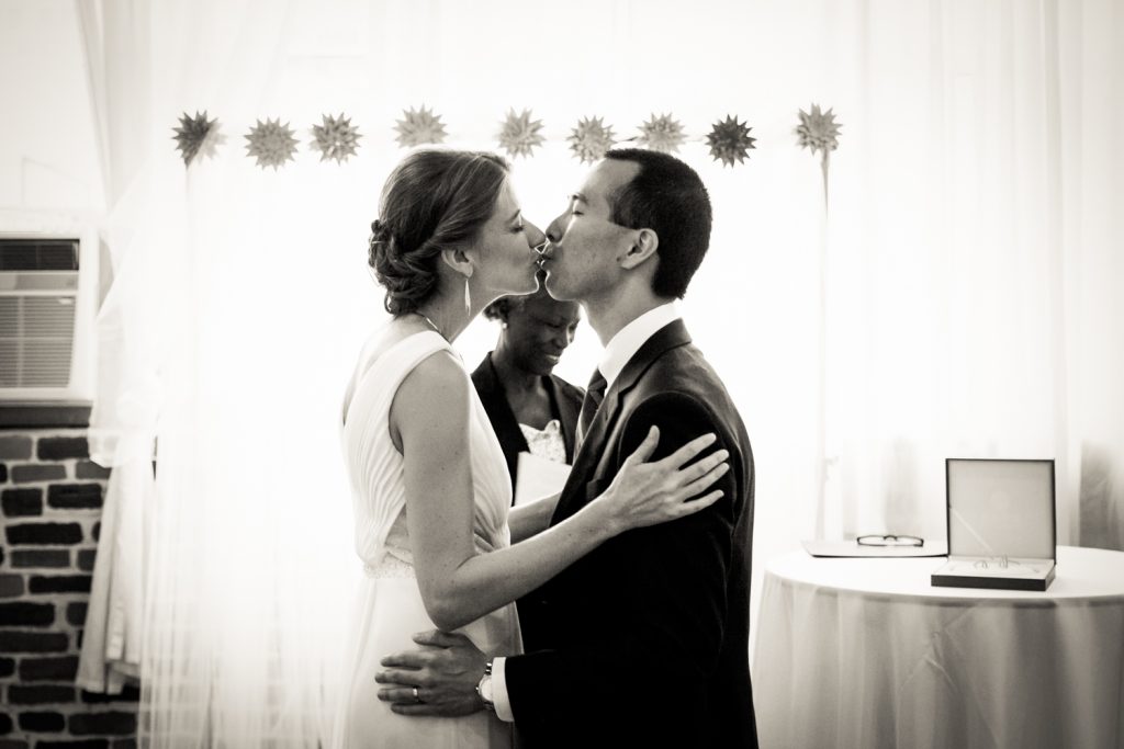 Black and white photo of bride and groom kissing after Astoria wedding ceremony