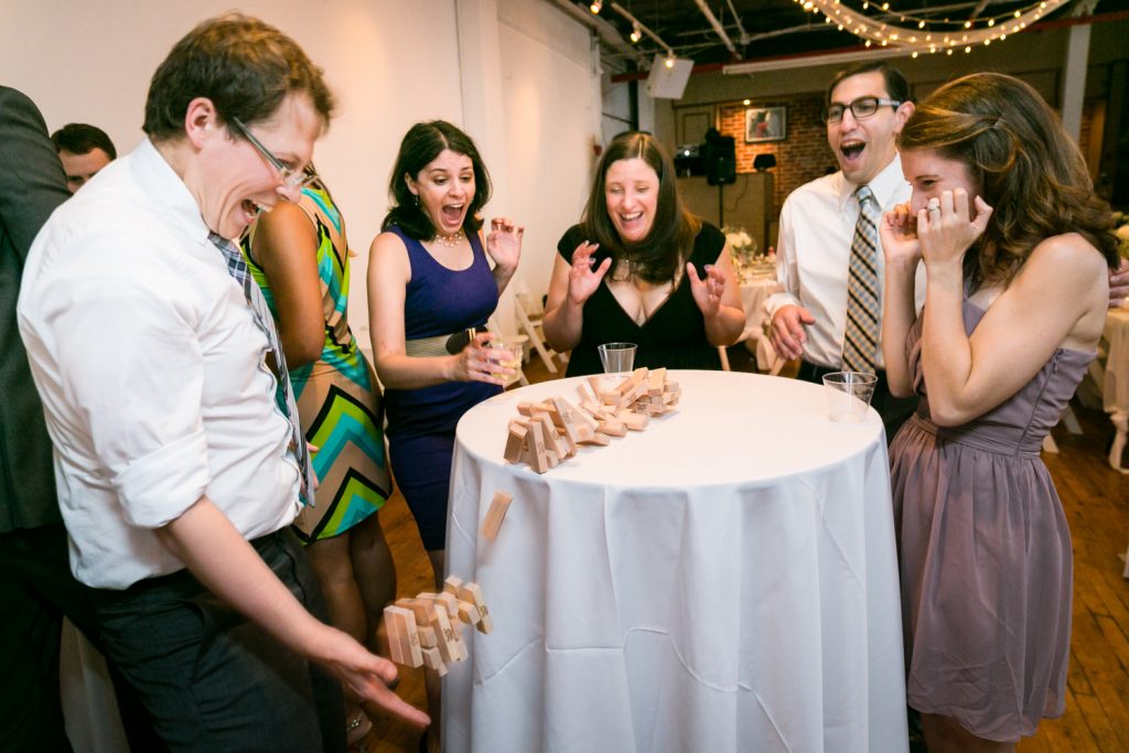 Wedding guests watching a tower of Jenga blocks falling for an article on event entertainment ideas
