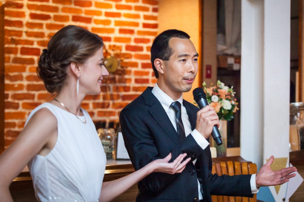 Bride holding groom's arm during speech at Astoria wedding reception