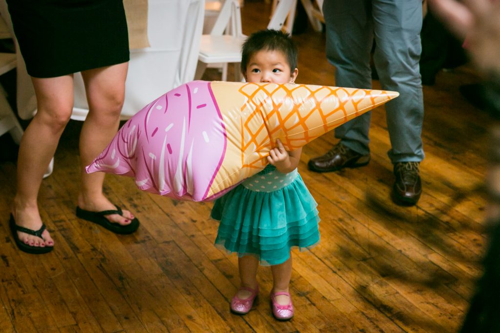 Little girl chewing on an inflated ice cream cone at Astoria wedding reception