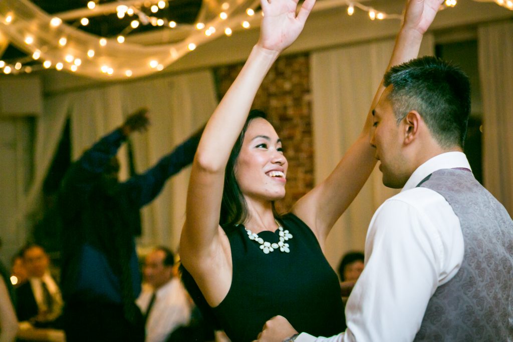 Female guest dancing with arms raised at Astoria wedding reception
