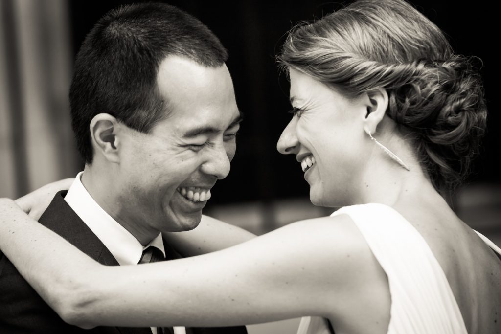 Black and white photo of bride and groom laughing at Astoria wedding reception