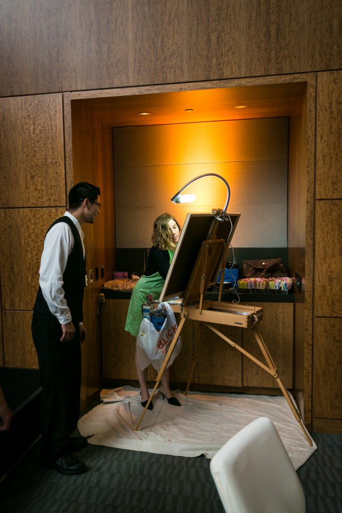 Guest watching as artist paints on an easel for an article on event entertainment ideas