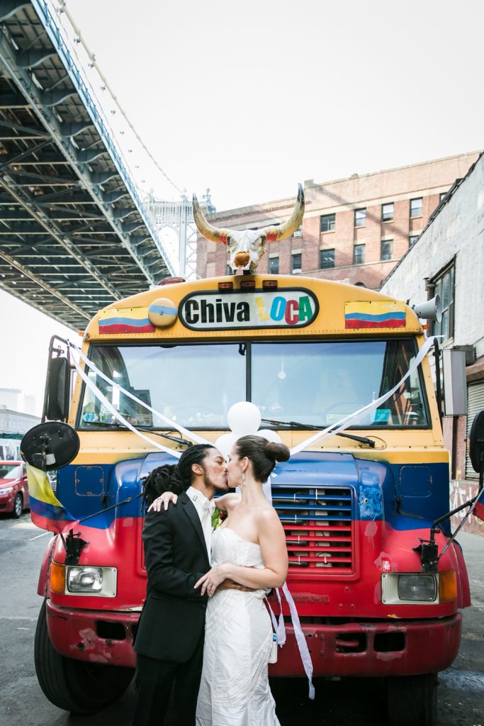 Bride and groom kissing in front of chiva loca bus at a DUMBO Loft wedding