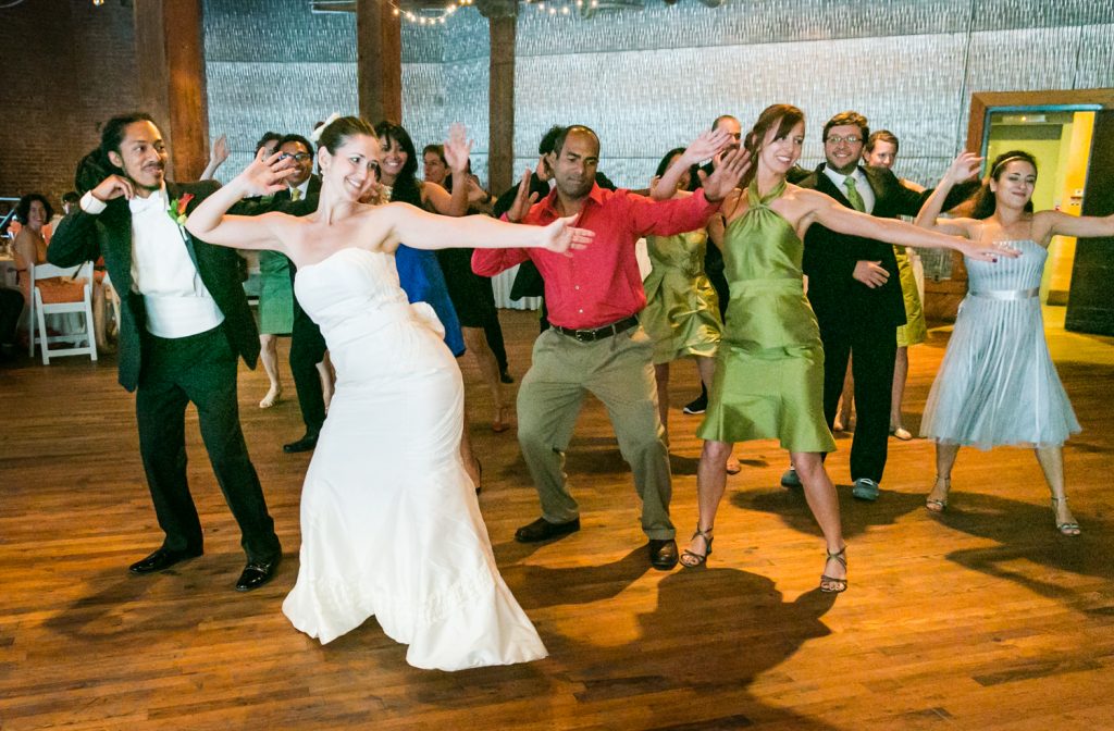 Bride and guests dancing with arms raised at a DUMBO Loft wedding