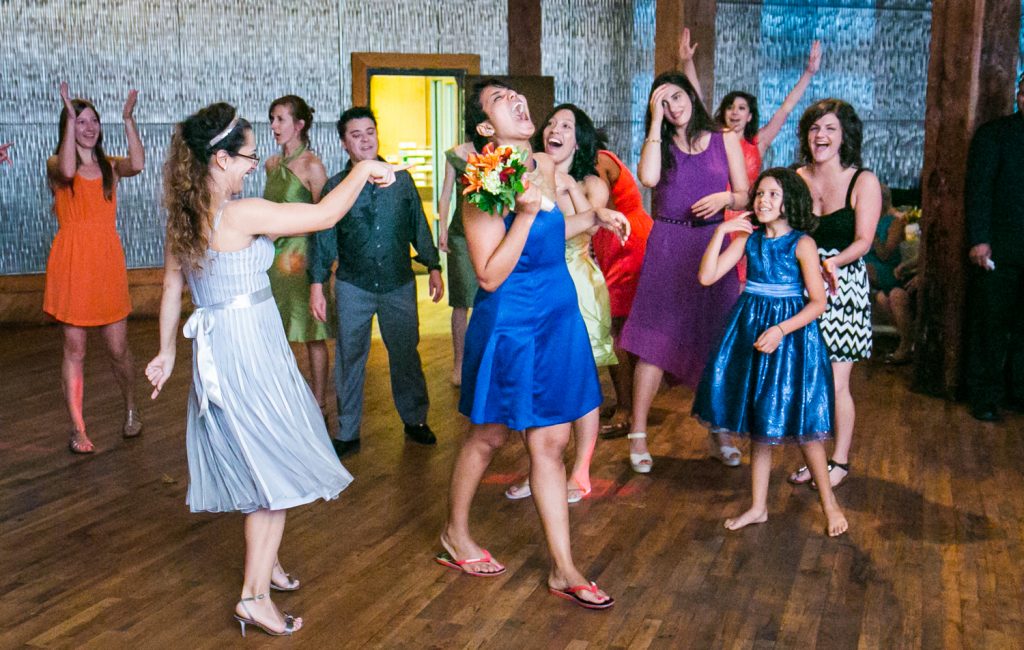 Female celebrating after catching bouquet at a DUMBO Loft wedding