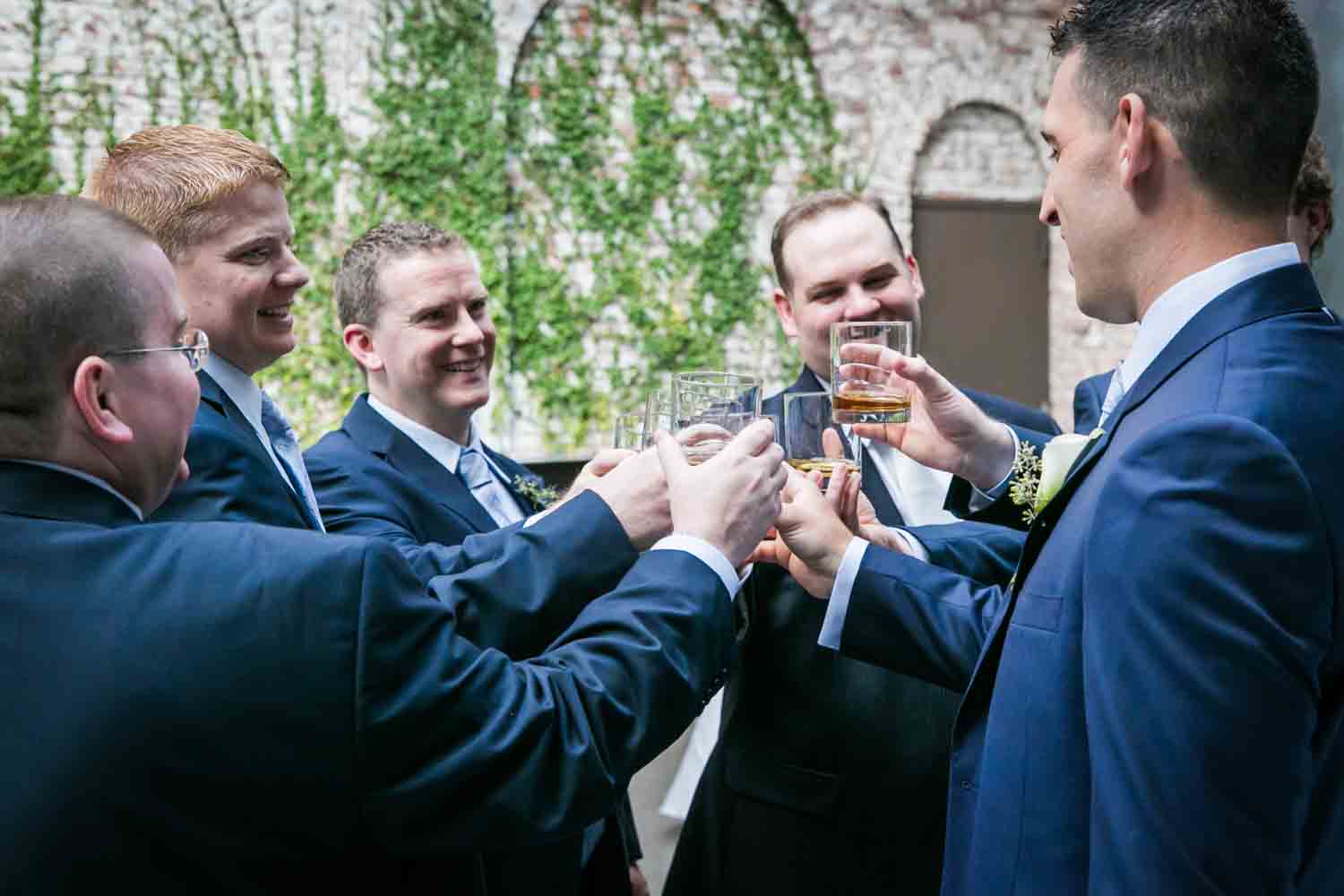 Groom and groomsmen cheering glasses for an article on how to become a wedding officiant in NYC