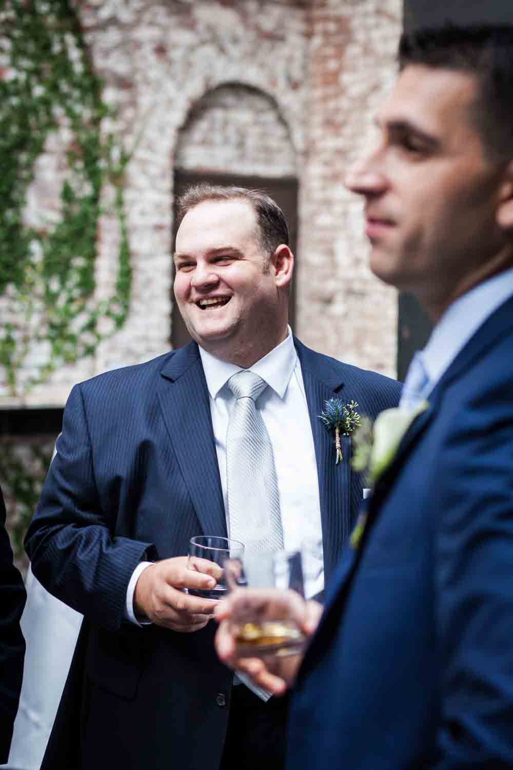 Groomsmen talking with other groomsmen and holding glass of scotch