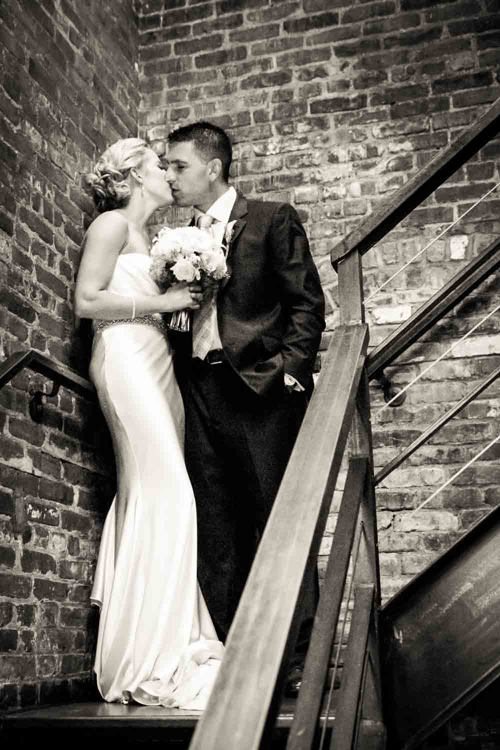Black and white photo of bride and groom in brick stairwell