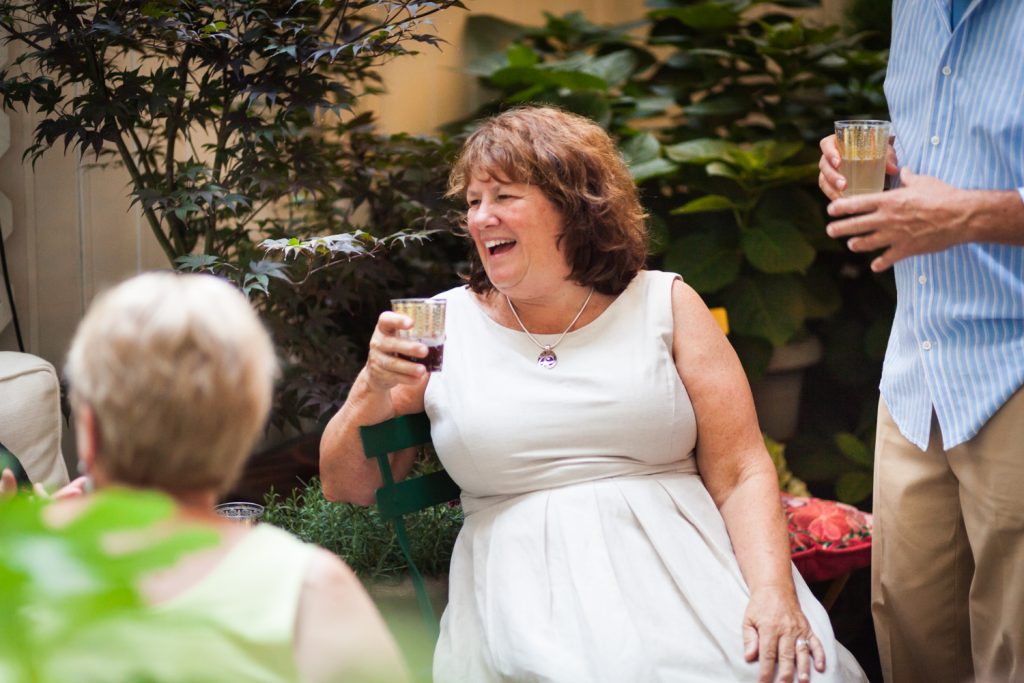 Woman wearing white dress holding drink at a NYC rehearsal dinner