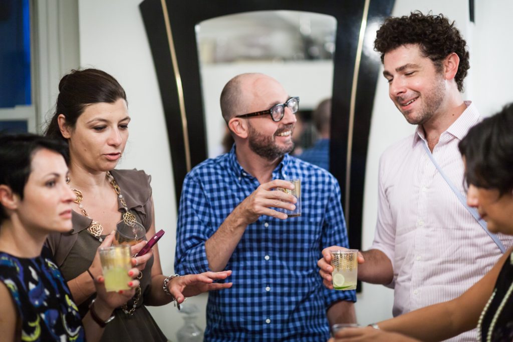 Five guests talking with drinks in hand at a NYC rehearsal dinner