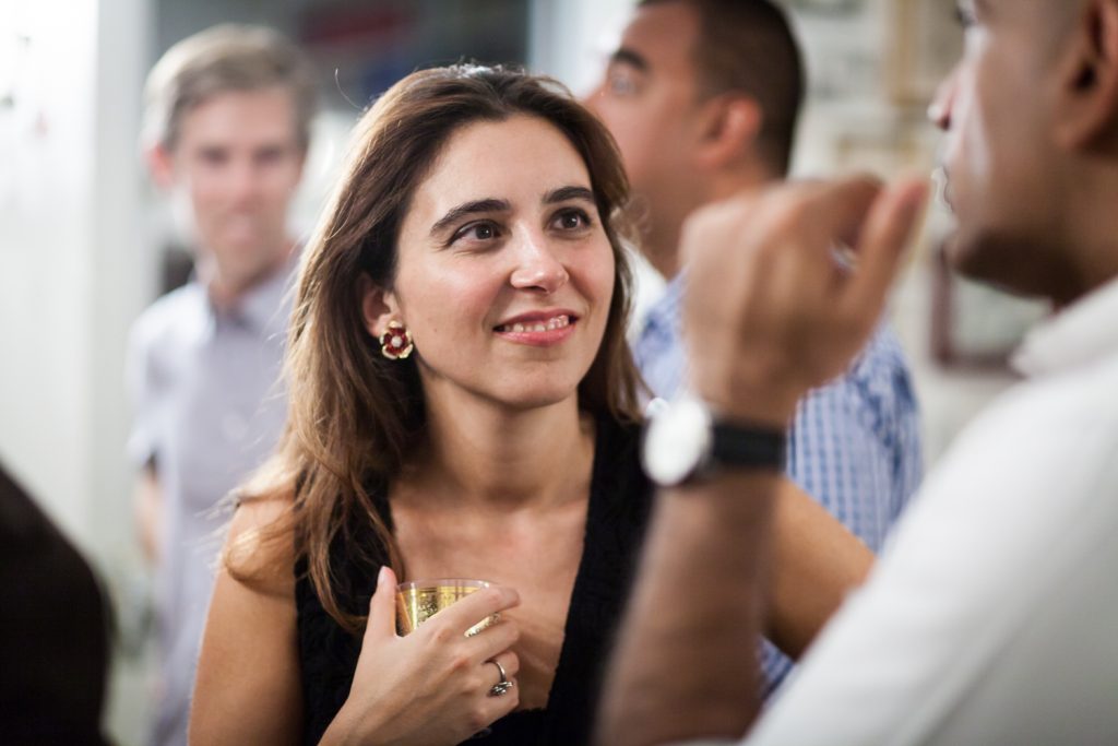 Woman holding drink and listening to guest at a NYC rehearsal dinner