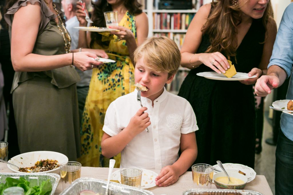 Young boy eating a Chinese dumpling at a NYC rehearsal dinner