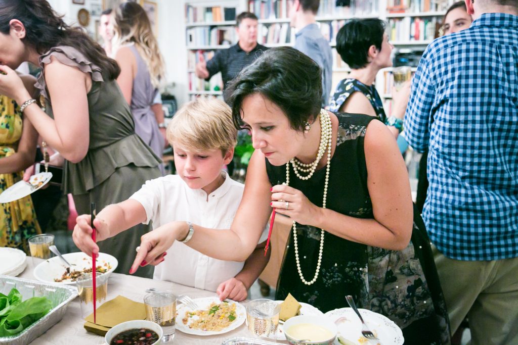 Woman pointing out food at a buffet to young boy