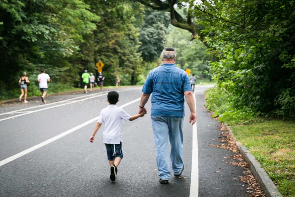Grandfather holding grandson's hand and walking down road