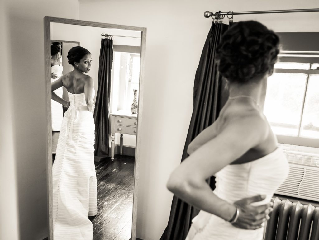 Bride looking at herself in the mirror for an article on when should my wedding photographer arrive