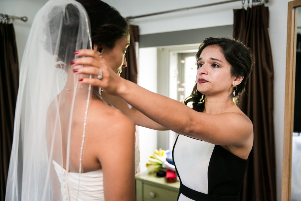 Bridesmaid crying and adjusting bride's veil