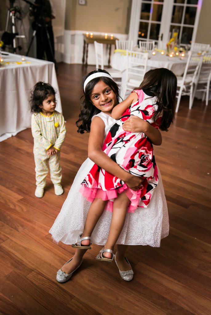 Flower girl lifting up little girl with baby in background