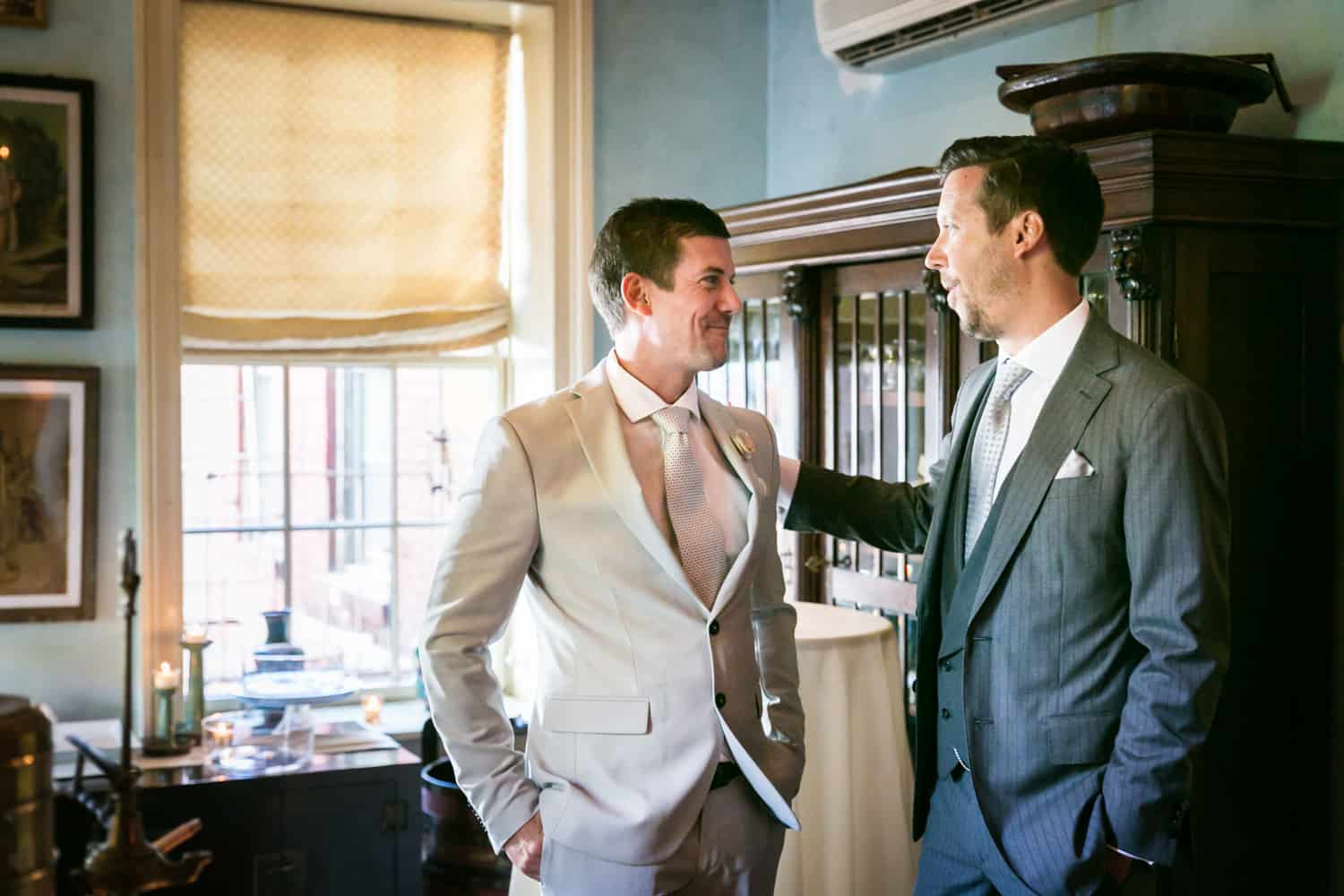 Groom and best man standing by window at a 632 on Hudson wedding