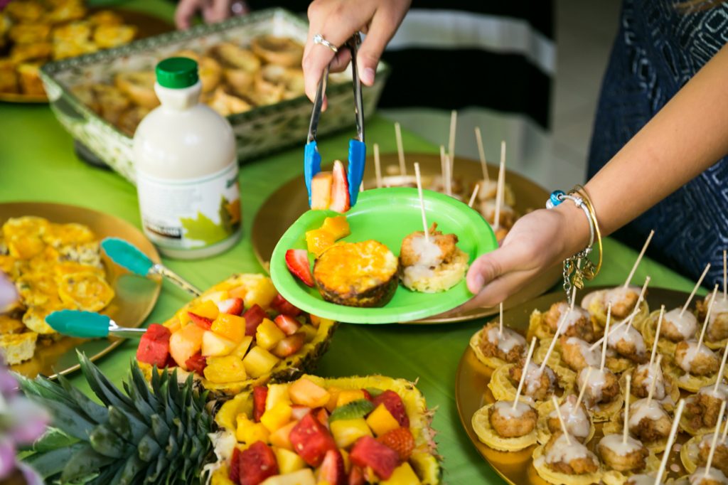 Hands putting food on a green plate at a Florida bridal shower