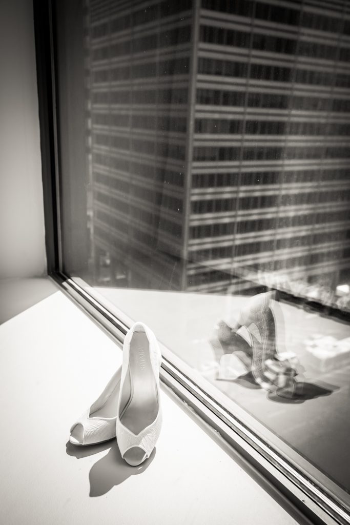 Black and white photo of white heels reflected in window