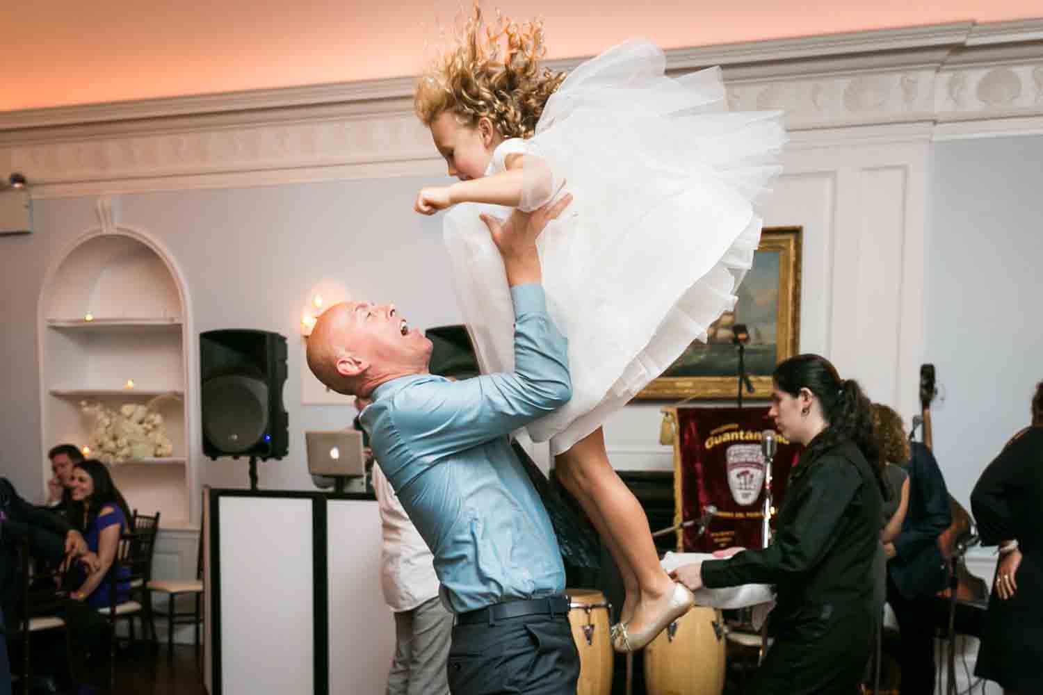 Man throwing little girl up in the air at wedding reception
