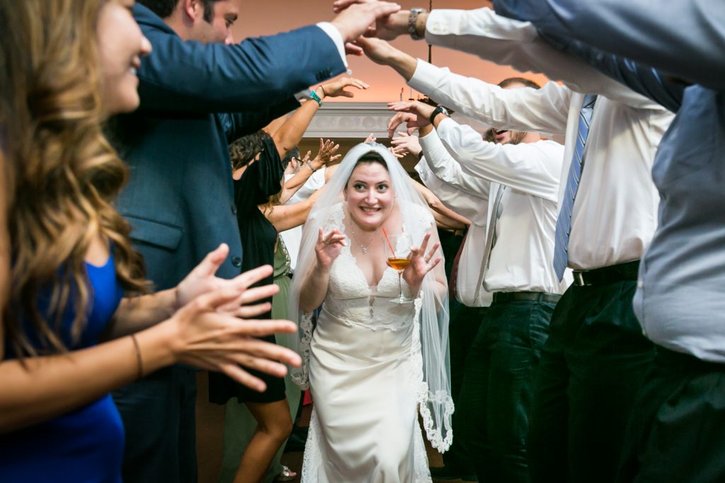 Bride going under arch of guest arms at India House wedding