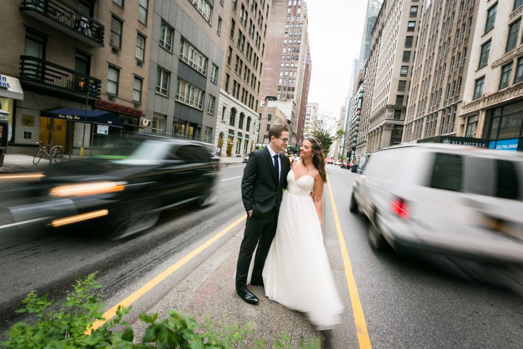 Bride and groom in focus with cars zooming by out of focus