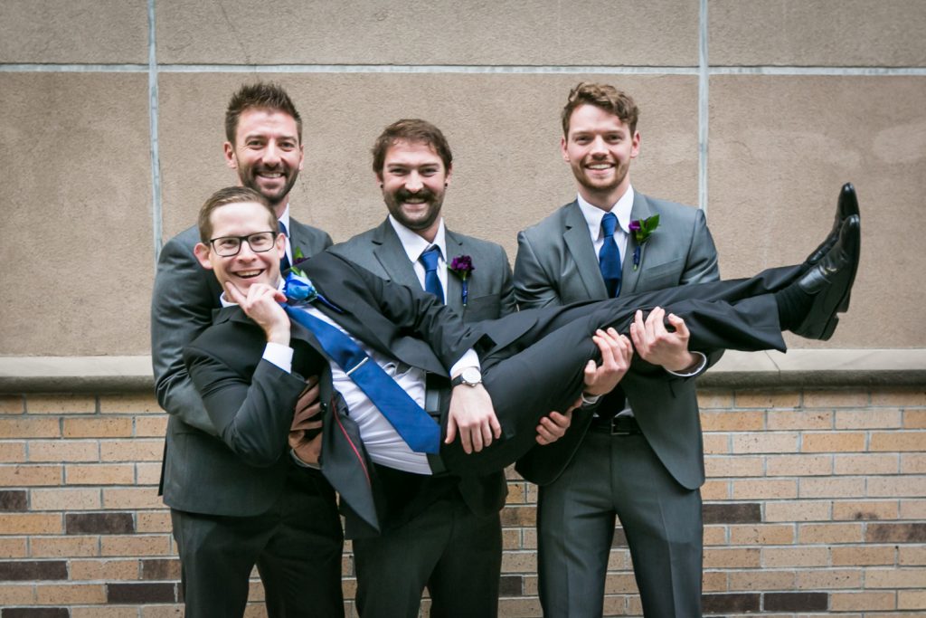 Portrait of groomsmen holding up groom