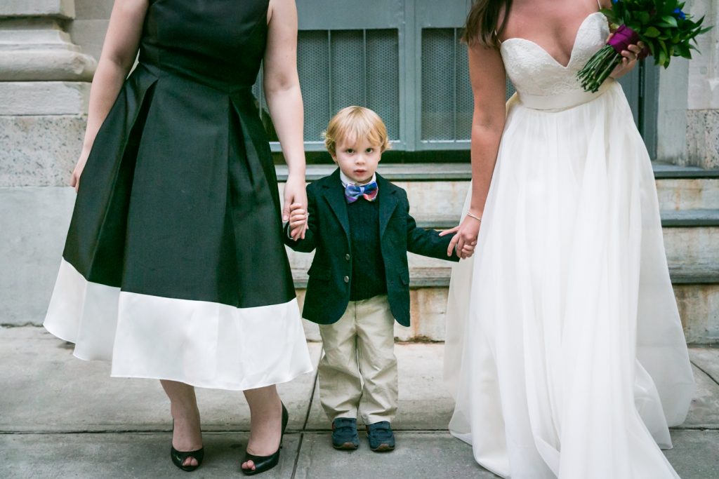 Close up photo of little boy holding hands of two women