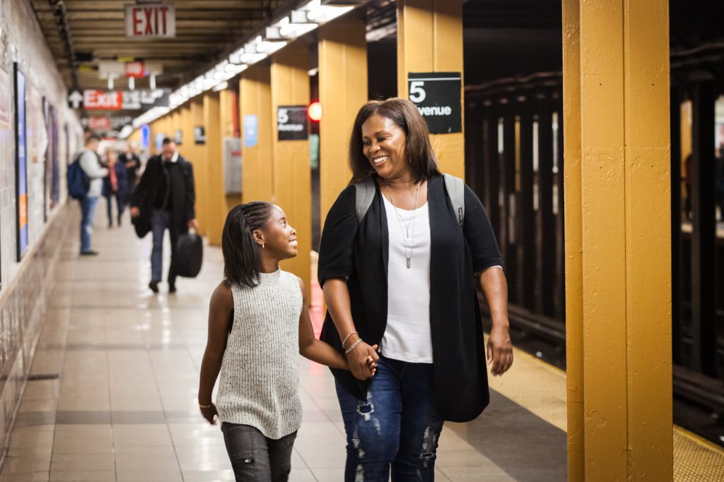 Mother and daughter holding hands and walking on subway platform