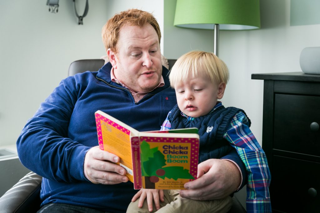 Father reading book to little blond haired boy