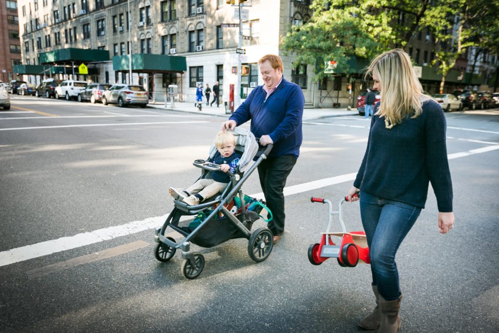 Couple pushing child in stroller across street in NYC