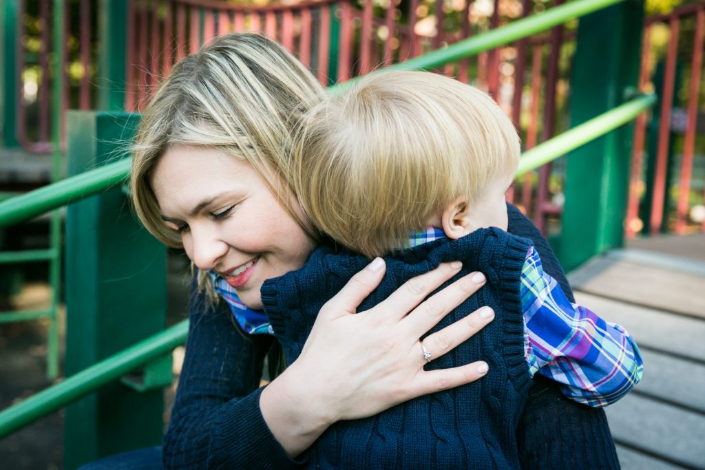 Central Park family photos of mother hugging little boy on playground equipment